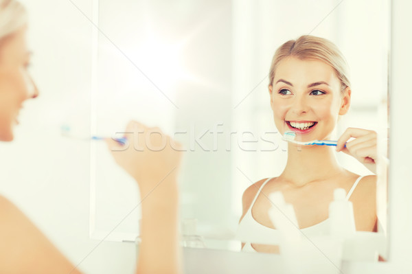 Stock photo: woman with toothbrush cleaning teeth at bathroom