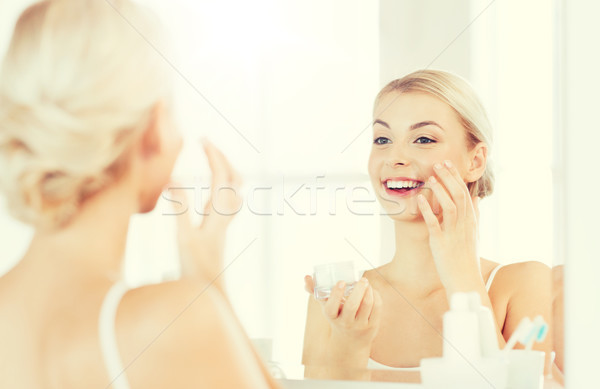Boldog nő jelentkezik krém arc fürdőszoba Stock fotó © dolgachov