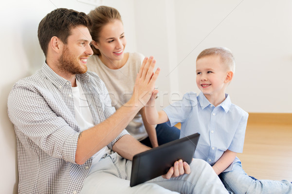 family with tablet pc at new home making high five Stock photo © dolgachov