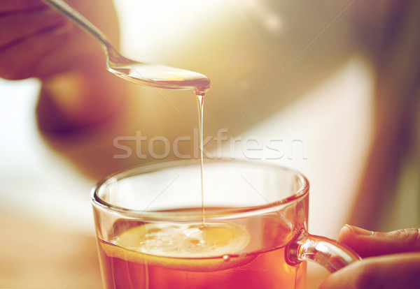 close up of woman adding honey to tea with lemon Stock photo © dolgachov