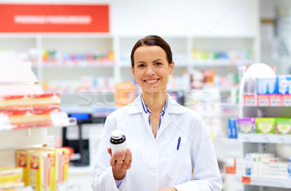 happy female apothecary with drug at pharmacy Stock photo © dolgachov