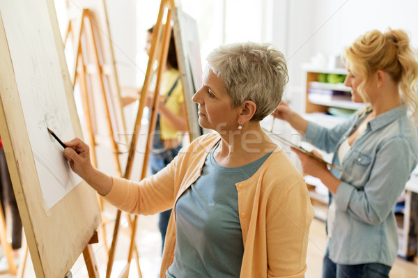 senior woman drawing on easel at art school studio Stock photo © dolgachov