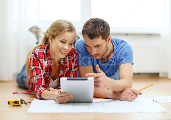 smiling couple looking at tablet pc at home Stock photo © dolgachov