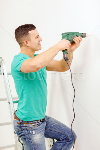 man with electric drill making hole in wall Stock photo © dolgachov