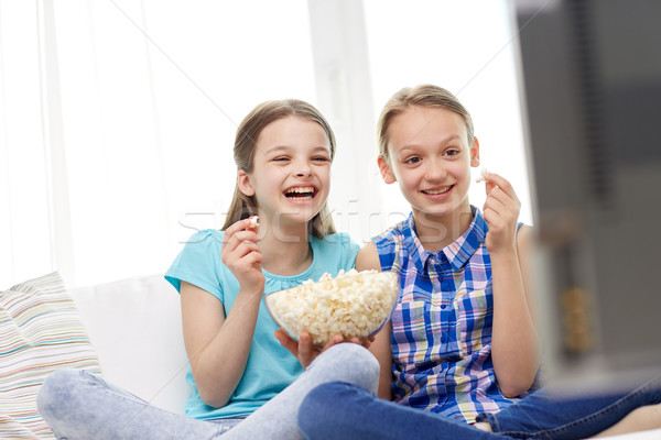 happy girls with popcorn watching tv at home Stock photo © dolgachov