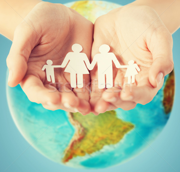 human hands holding paper family over earth globe Stock photo © dolgachov