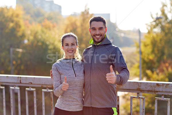 Stock photo: smiling couple showing thumbs up outdoors