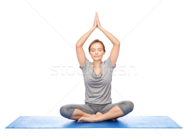 woman making yoga meditation in lotus pose on mat Stock photo © dolgachov