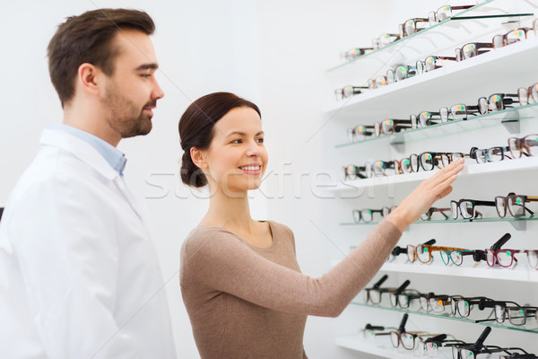 Stock photo: woman showing glasses to optician at optics store