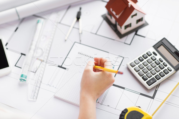 Stock photo: close up of hand on blueprint writing to notebook