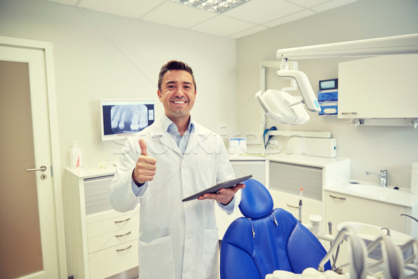 happy dentist showing thumbs up with tablet pc Stock photo © dolgachov