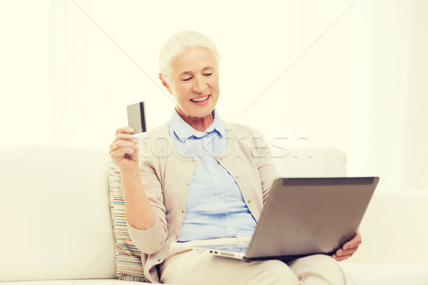 Stock photo: senior woman with laptop and credit card at home