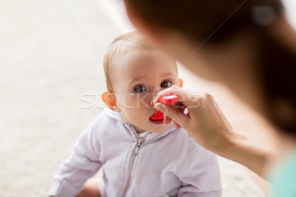 mother with spoon feeding little baby at home Stock photo © dolgachov