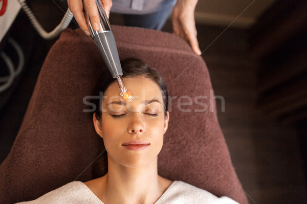 woman with microcurrent face massager in spa Stock photo © dolgachov