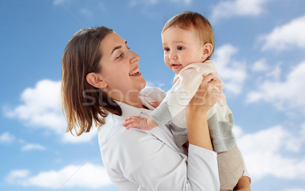 happy doctor or pediatrician with baby over sky Stock photo © dolgachov