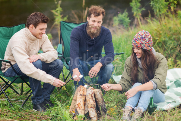 smiling tourists cooking marshmallow in camping Stock photo © dolgachov