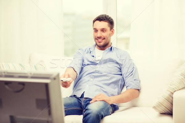 smiling man with tv remote control at home Stock photo © dolgachov