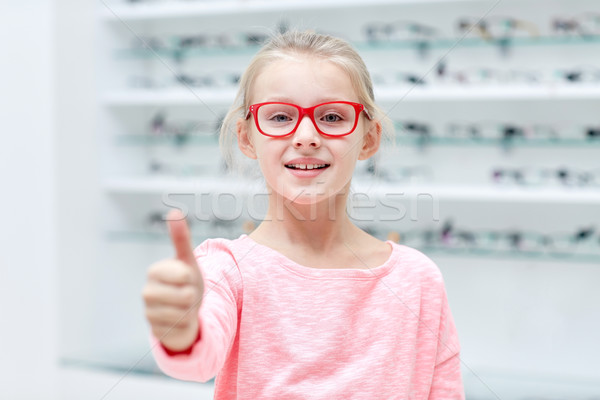 girl in glasses at optics store showing thumbs up Stock photo © dolgachov