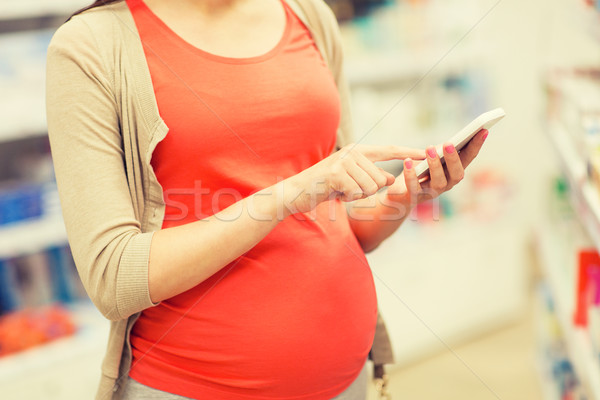 pregnant woman with smartphone at pharmacy Stock photo © dolgachov