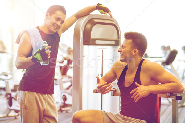 smiling men exercising on gym machine Stock photo © dolgachov