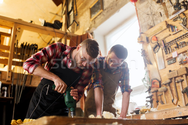 carpenters with drill drilling plank at workshop Stock photo © dolgachov