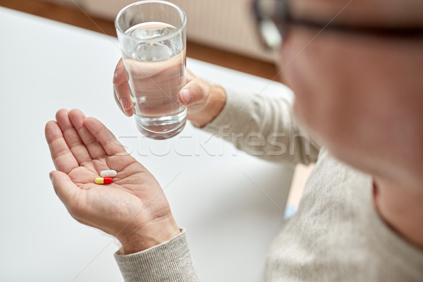 close up of old man hands with pills and water Stock photo © dolgachov