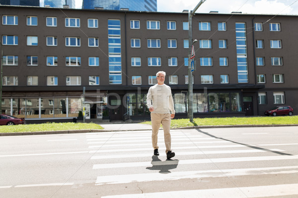 senior man walking along city crosswalk Stock photo © dolgachov