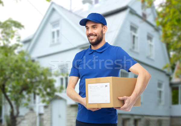 happy delivery man with parcel box over house Stock photo © dolgachov