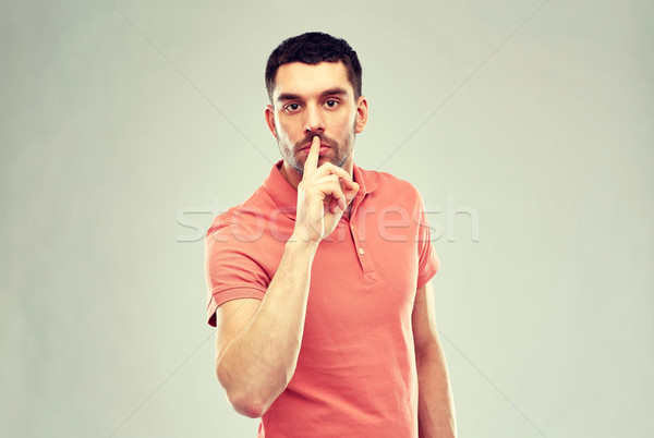 young man making hush sign over gray background Stock photo © dolgachov