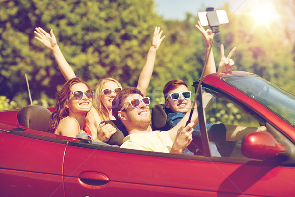 friends driving in cabriolet car and taking selfie Stock photo © dolgachov