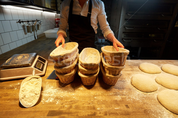 baker with baskets for bread dough at bakery Stock photo © dolgachov