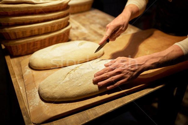 baker making bread and cutting dough at bakery Stock photo © dolgachov