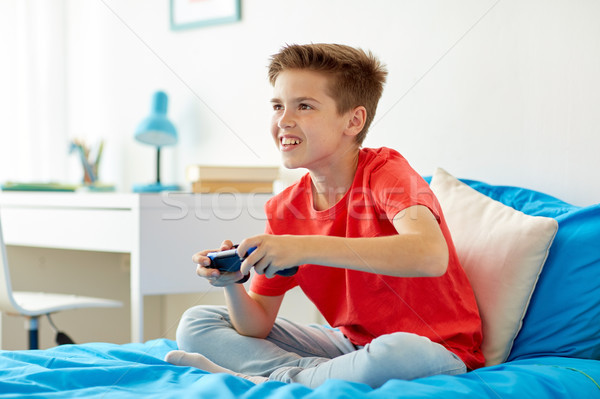 happy boy with gamepad playing video game at home Stock photo © dolgachov