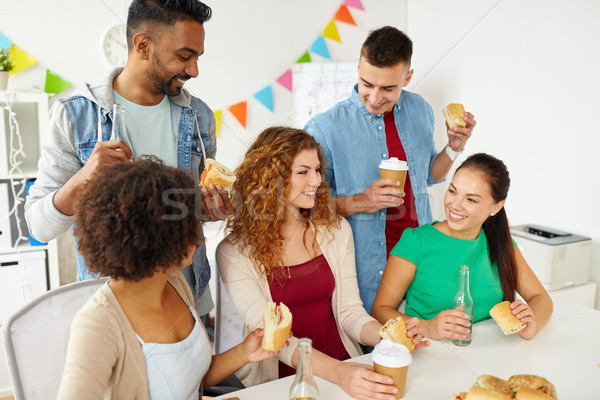 happy friends or team eating at office party Stock photo © dolgachov