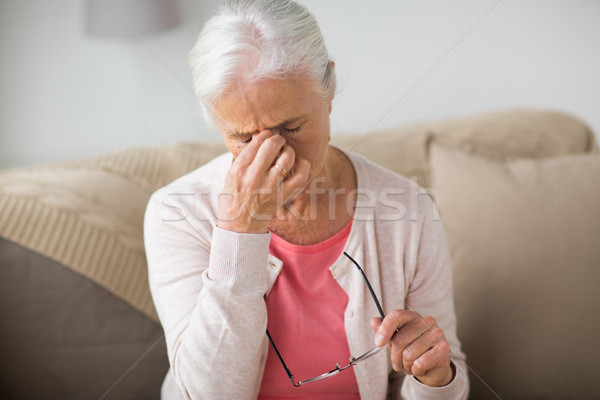 Stock photo: senior woman with glasses having headache at home