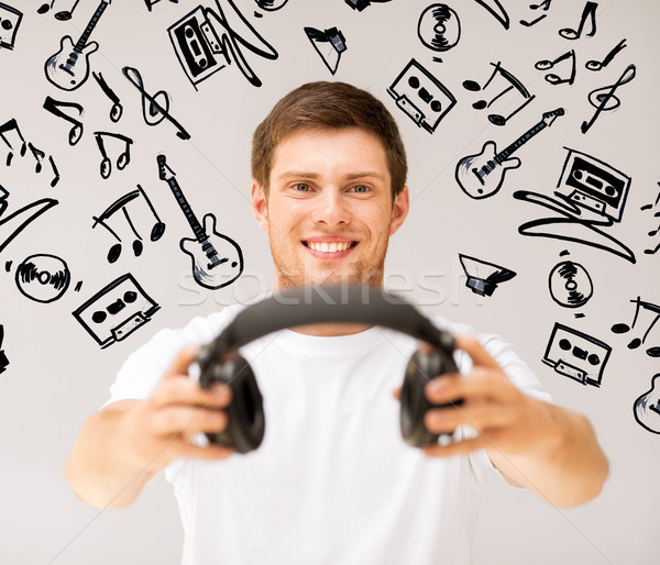 young smiling man offering headphones Stock photo © dolgachov