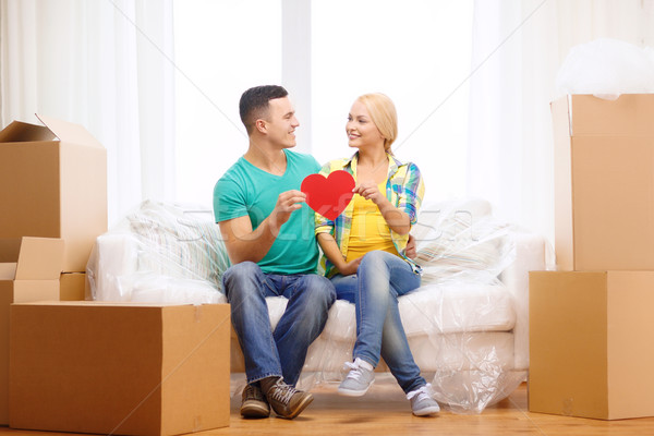 smiling couple with red heart on sofa in new home Stock photo © dolgachov