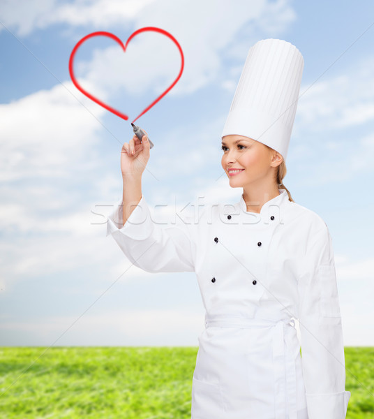 smiling female chef drawing red heart on air Stock photo © dolgachov
