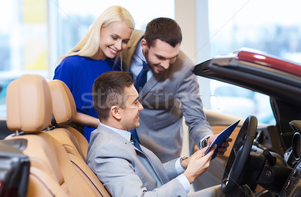 happy couple with car dealer in auto show or salon Stock photo © dolgachov