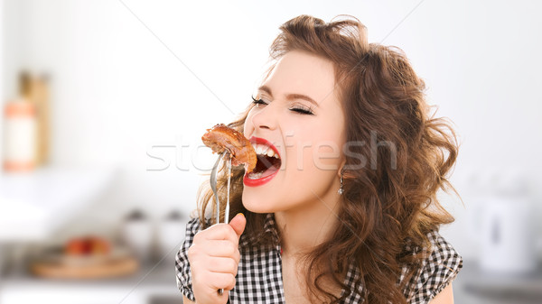 hungry young woman eating meat on fork in kitchen Stock photo © dolgachov