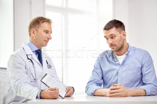 doctor and patient with cardiogram on clipboard Stock photo © dolgachov