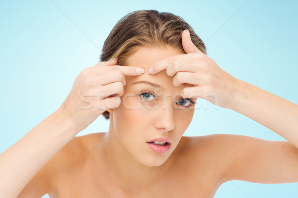 young woman squeezing pimple on her face Stock photo © dolgachov