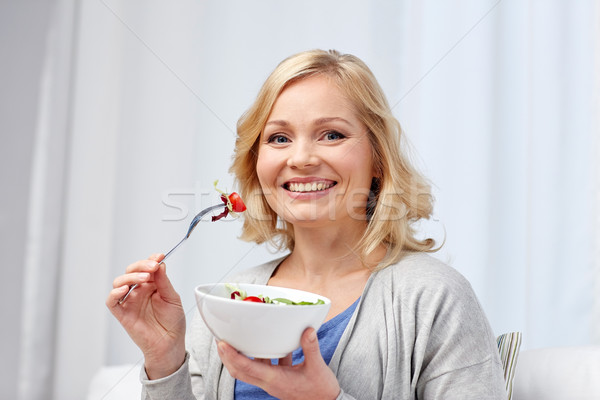 smiling middle aged woman eating salad at home Stock photo © dolgachov