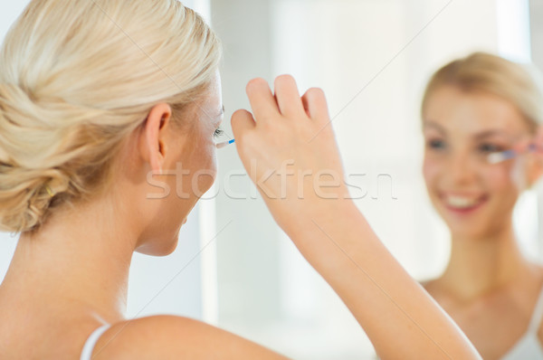 woman fixing makeup with cotton swab at bathroom Stock photo © dolgachov