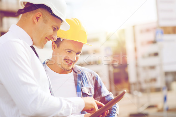 Stock photo: smiling builders in hardhats with tablet pc