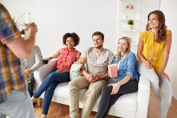 Stock photo: friends with popcorn and drinks talking at home