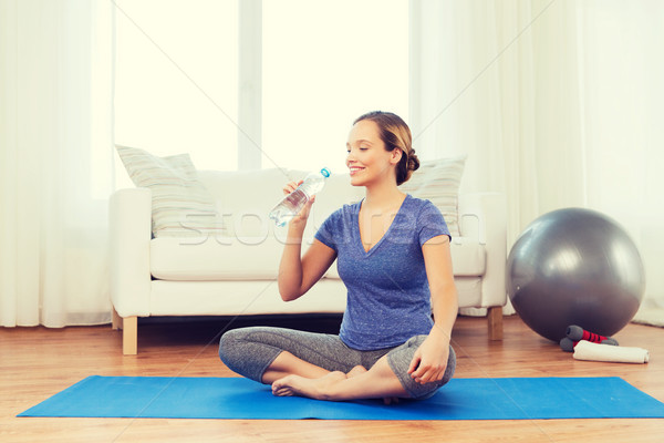 happy woman with water bottle exercising at home Stock photo © dolgachov