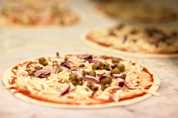 raw pizza with grated cheese on table at pizzeria Stock photo © dolgachov