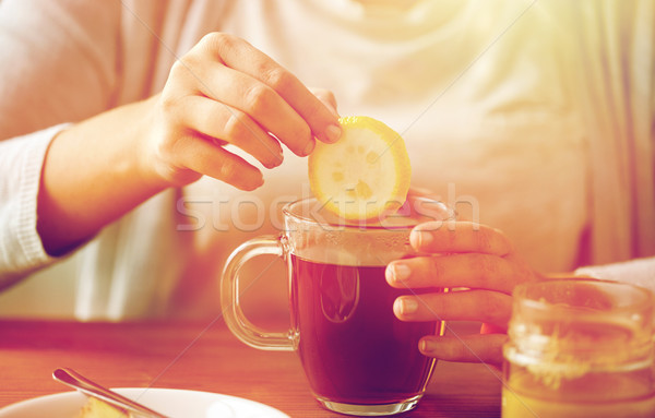 close up of woman adding lemon to tea with honey Stock photo © dolgachov