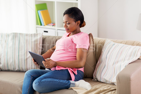 Stock photo: happy pregnant woman with tablet pc at home
